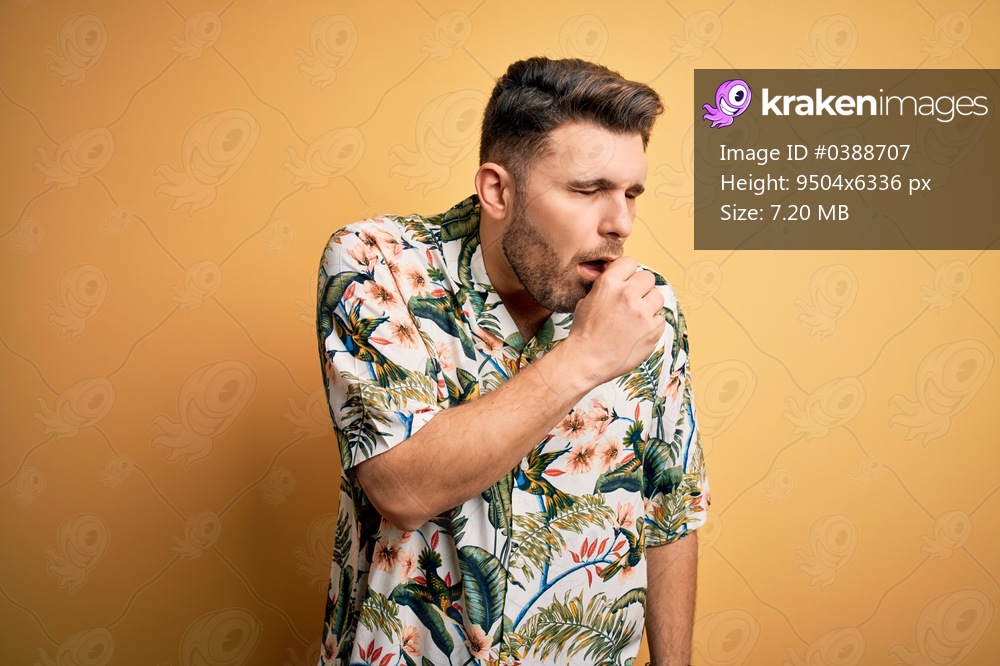 Young man with blue eyes on vacation wearing floral summer shirt over yellow background feeling unwell and coughing as symptom for cold or bronchitis. Health care concept.