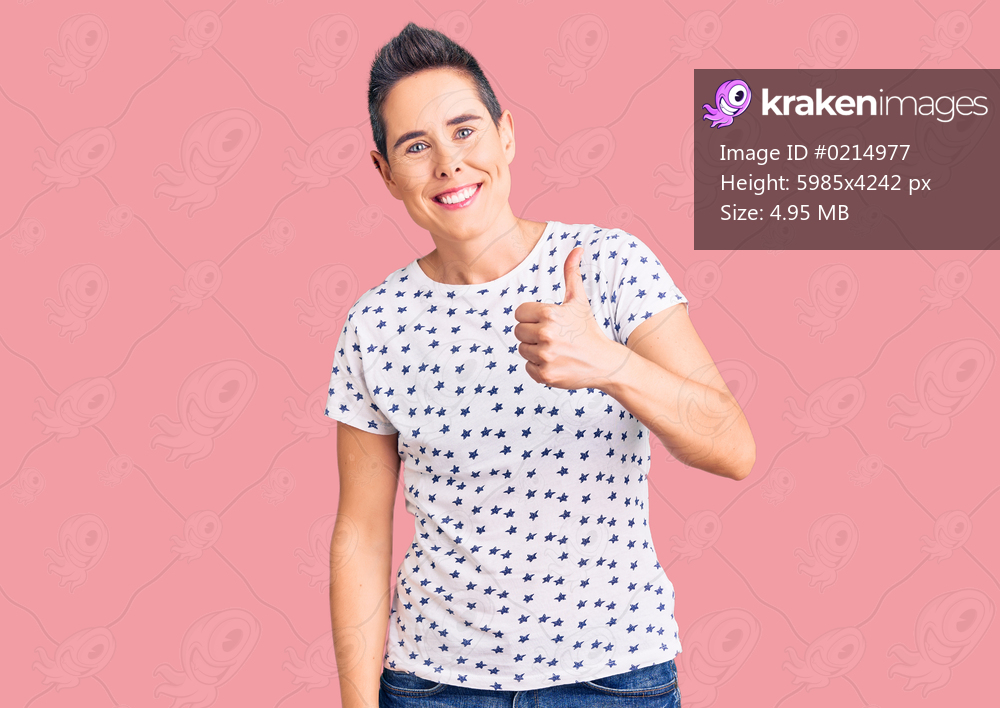 Young woman with short hair wearing casual clothes smiling happy and positive, thumb up doing excellent and approval sign 