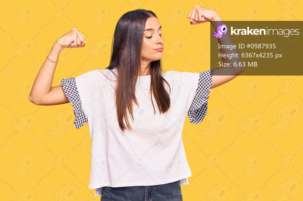 Young hispanic woman wearing casual clothes showing arms muscles smiling proud. fitness concept. 