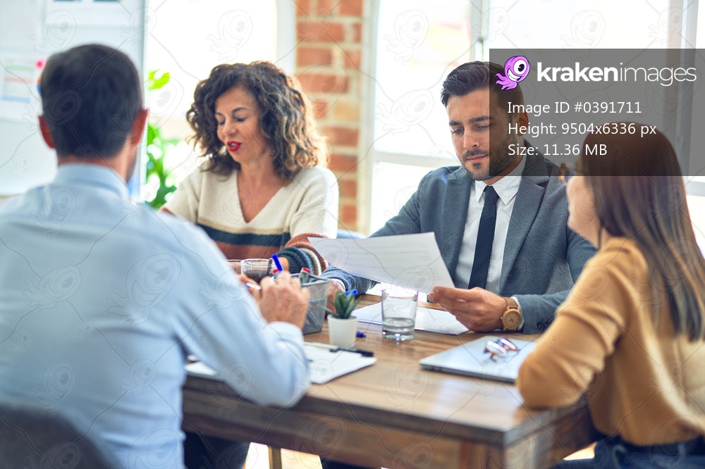 Group of business workers working together. Sitting on desk reading documents at the office