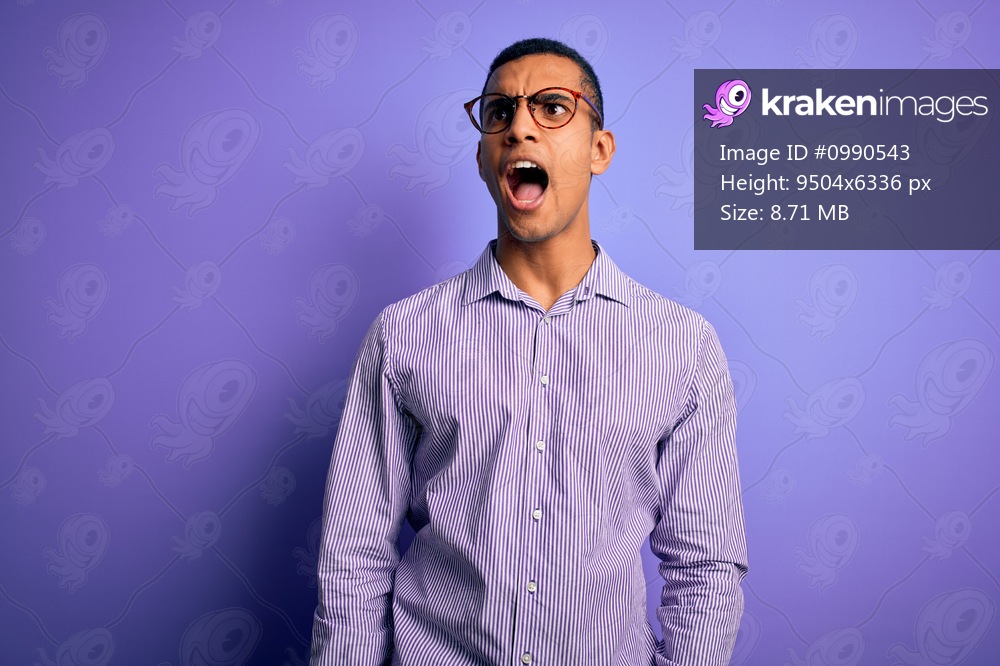 Handsome african american man wearing striped shirt and glasses over purple background angry and mad screaming frustrated and furious, shouting with anger. Rage and aggressive concept.