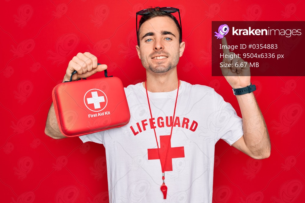Young handsome lifeguard man wearing t-shirt with red cross and whistle holding first aid kit surprised with an idea or question pointing finger with happy face, number one