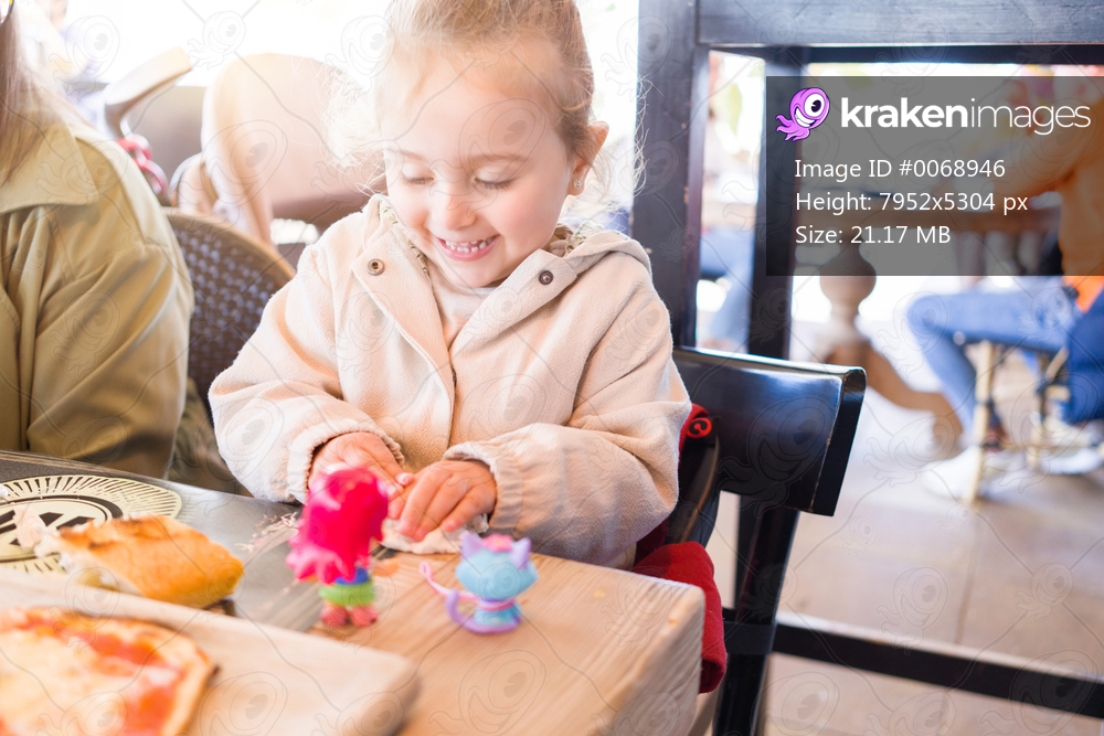 Beautiful toddler child girl sitting on baby highchair  playing with toys on the table