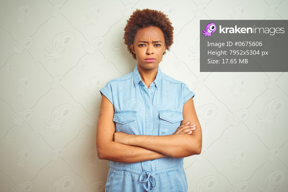 Young beautiful african american woman with afro hair over isolated background skeptic and nervous, disapproving expression on face with crossed arms. Negative person.
