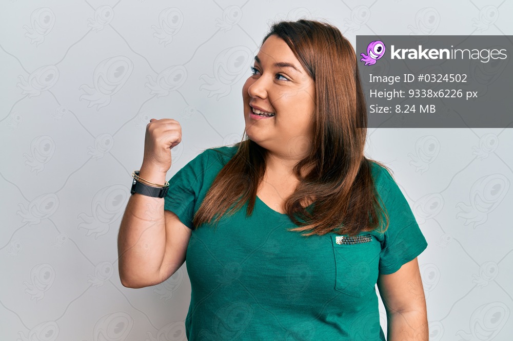 Beautiful brunette plus size woman wearing casual clothes pointing thumb up to the side smiling happy with open mouth 