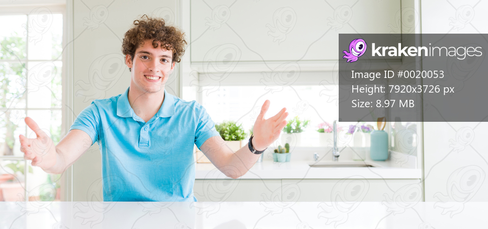 Wide shot of young handsome man at home looking at the camera smiling with open arms for hug. Cheerful expression embracing happiness.