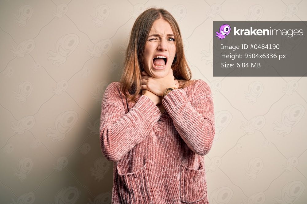 Young beautiful redhead woman wearing pink casual sweater over isolated white background shouting suffocate because painful strangle. Health problem. Asphyxiate and suicide concept.