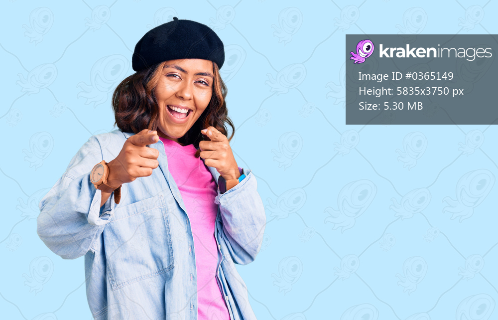 Young beautiful mixed race woman wearing french look with beret pointing fingers to camera with happy and funny face. good energy and vibes. 