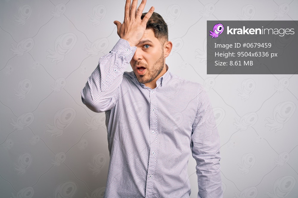 Young business man with blue eyes standing over isolated background surprised with hand on head for mistake, remember error. Forgot, bad memory concept.