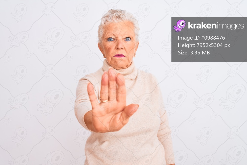Senior grey-haired woman wearing turtleneck sweater standing over isolated white background doing stop sing with palm of the hand. Warning expression with negative and serious gesture on the face.