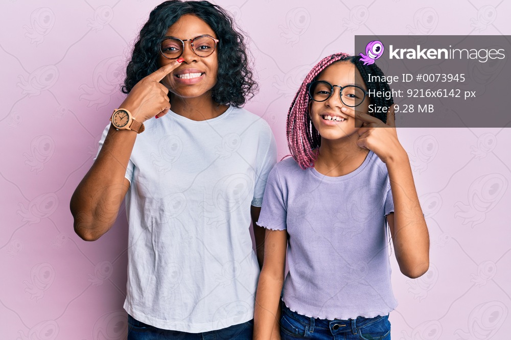 Beautiful african american mother and daughter wearing casual clothes and glasses pointing with hand finger to face and nose, smiling cheerful. beauty concept 