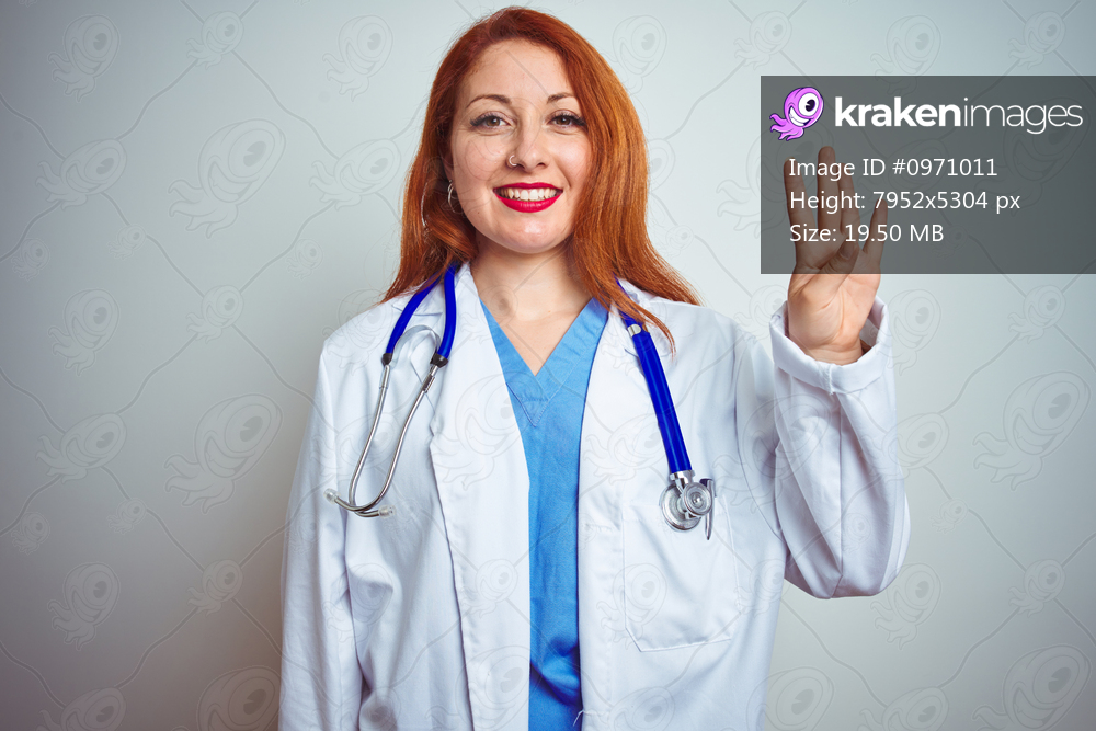 Young redhead doctor woman using stethoscope over white isolated background showing and pointing up with fingers number four while smiling confident and happy.