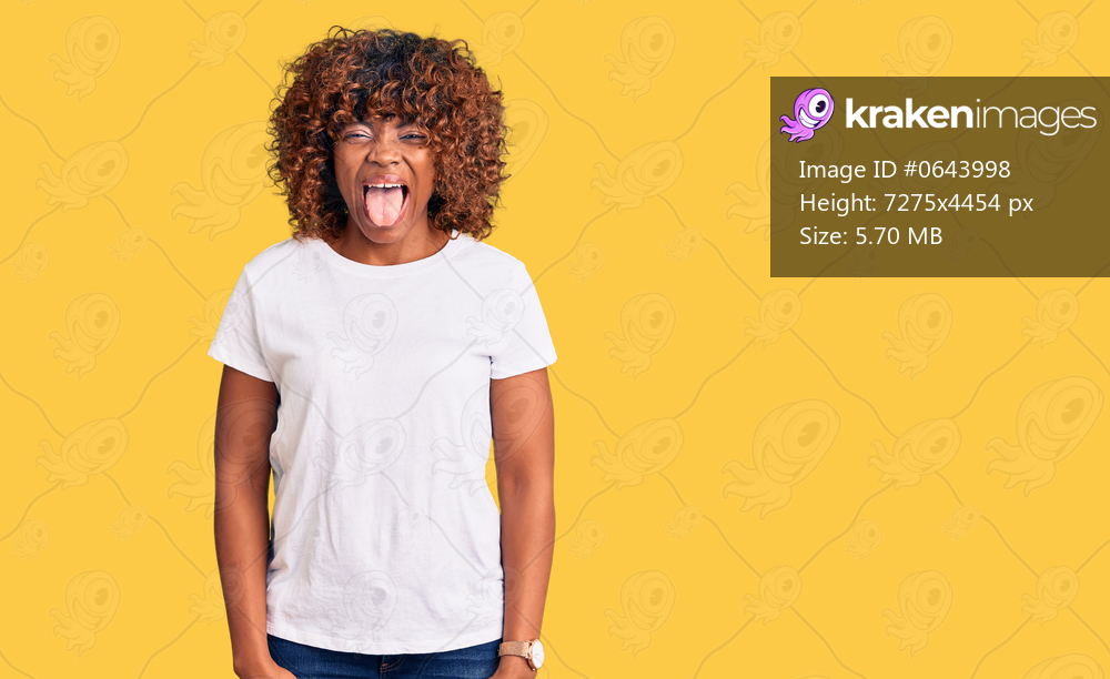 Young african american woman wearing casual white tshirt sticking tongue out happy with funny expression. emotion concept. 