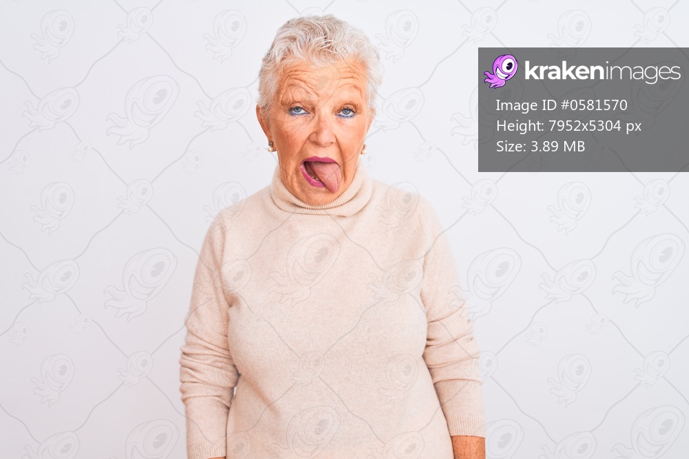 Senior grey-haired woman wearing turtleneck sweater standing over isolated white background sticking tongue out happy with funny expression. Emotion concept.