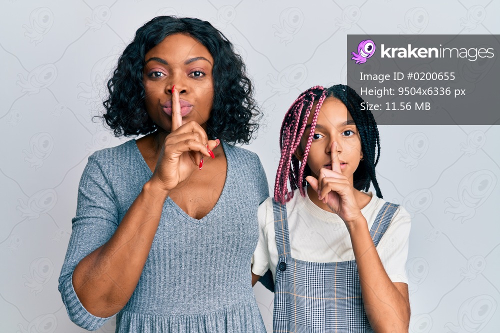 Beautiful african american mother and daughter wearing casual clothes and hugging asking to be quiet with finger on lips. silence and secret concept. 