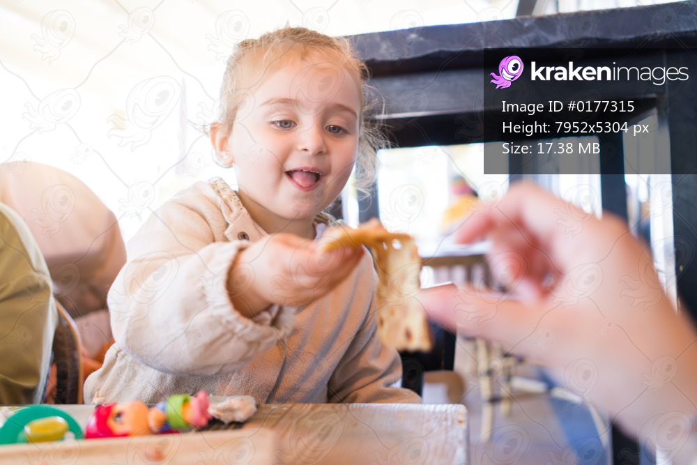 Beautiful toddler child girl sitting on baby highchair  playing with toys on the table